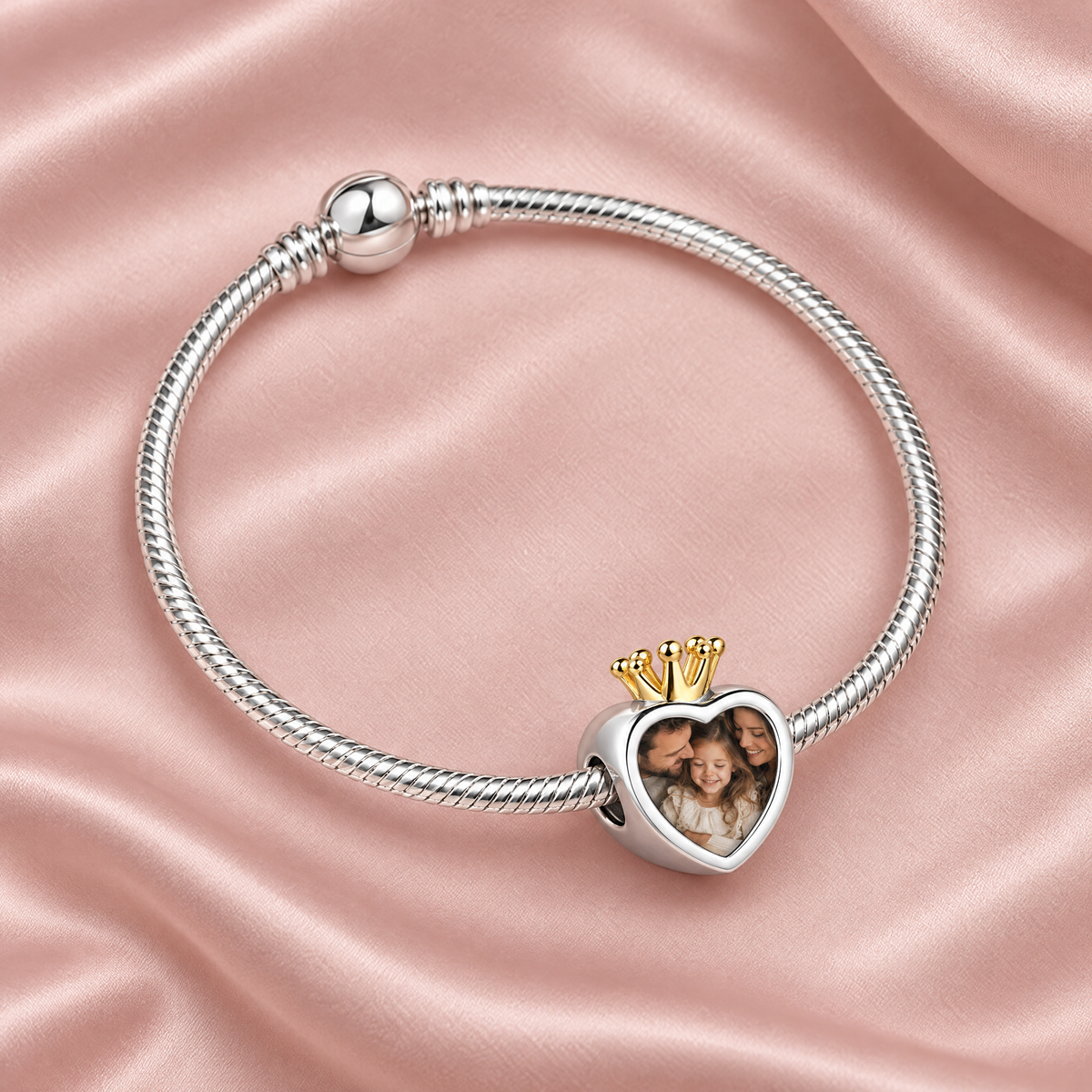 Personalized Custom Photo Engraved Crown Charm, on a charm bracelet laid on blush silk